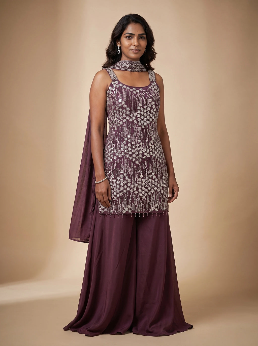 Model wearing a burgundy georgette sharara set with floral-inspired sequin and bead embellished top and matching dupatta