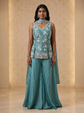 Model wearing a teal blue georgette floral sequin and cut-bead sharara set with matching dupatta